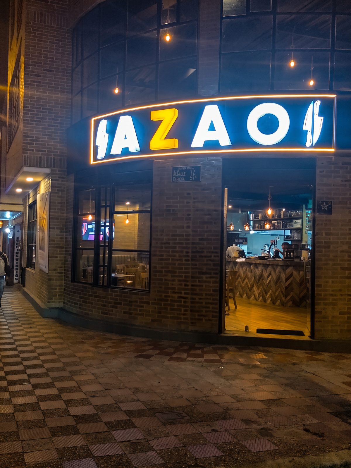 Fachada de Azao de noche con el letrero iluminado en la esquina