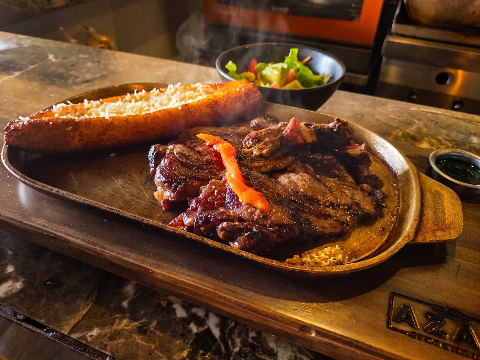 Bife a la parrilla con maduro gratinado, ensalada y chimichurri, en el mesón de la cocina de Azao