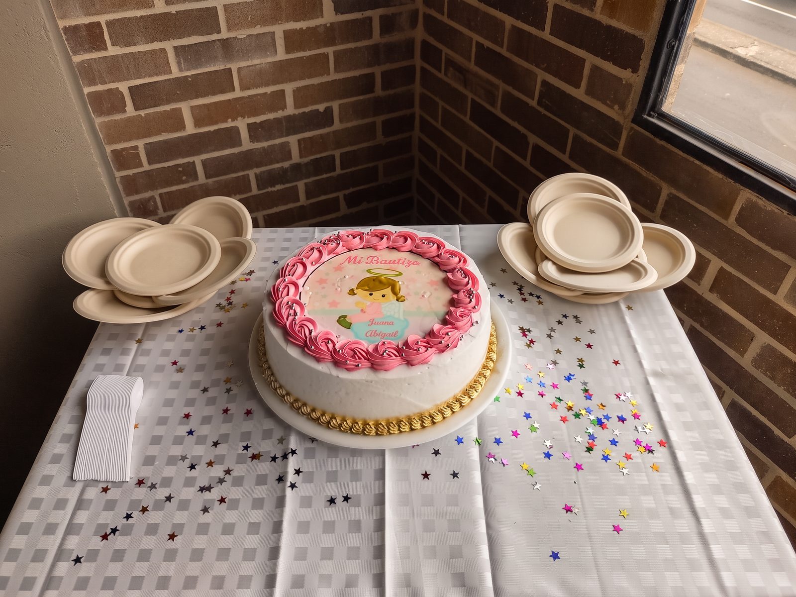 Torta de bautizo decorada sobre la mesa con platos y confeti
